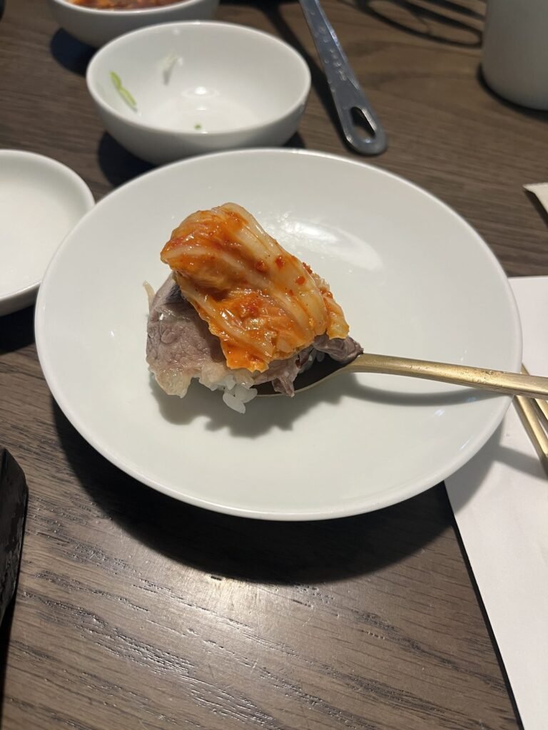 Beef from gomtang topped with kimchi on a spoon